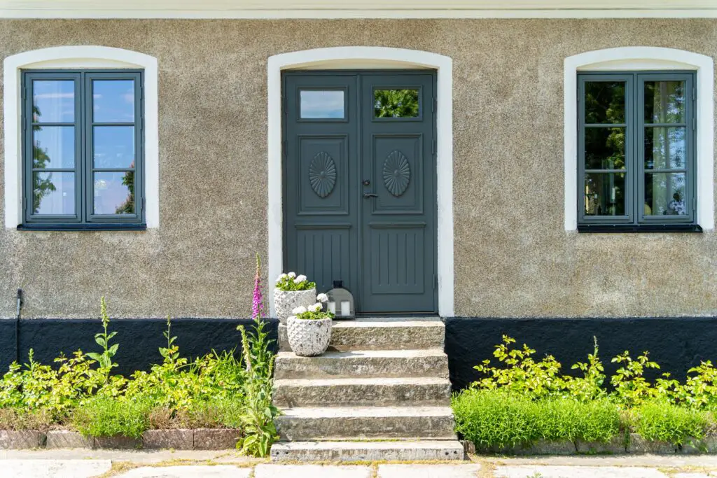 Image of Closed green wooden entrance door with stone stairs and concrete walls of the scandinavian style house